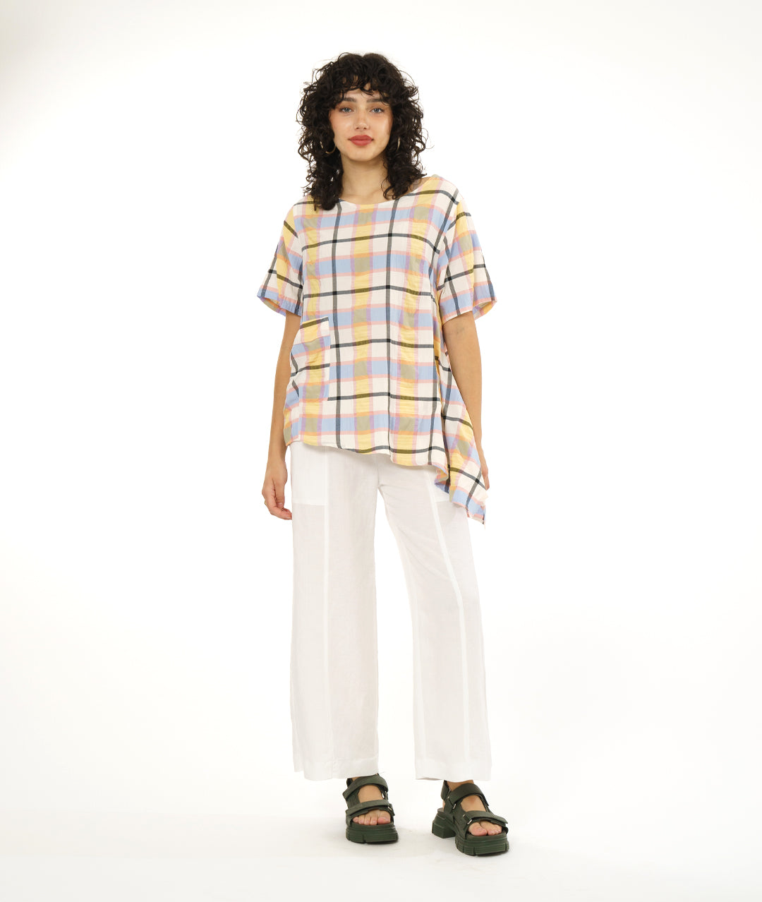 model in a wide leg white pant with an asymmetrical multi color plaid pullover top