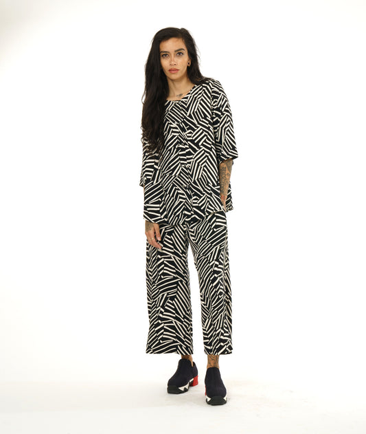 model in a black and white broken stripe print pant, worn with a collar less matching fabric button down blouse with 3/4 sleeves
