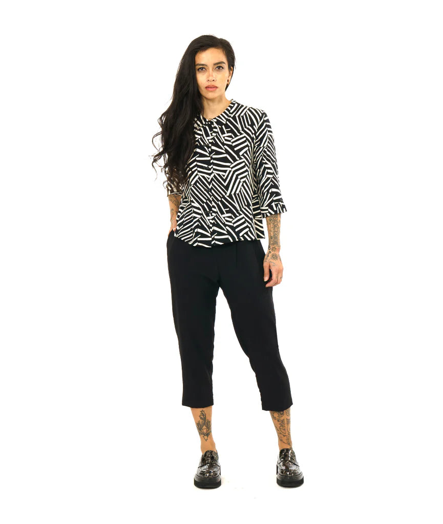 model wearing black and white design button up 3/4 sleeve top with black pants and loafers