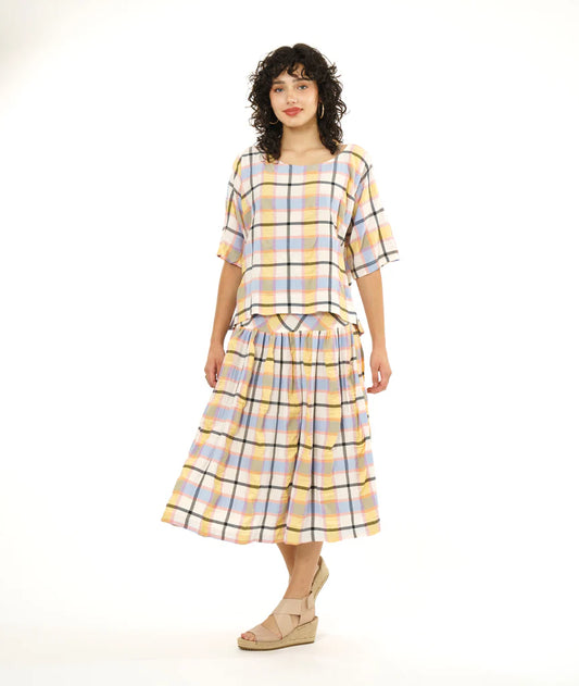 model wearing boxy and short top with dolman sleeves and a no shoulder seam in a plaid pastel pattern with a matching midi skirt and sandals