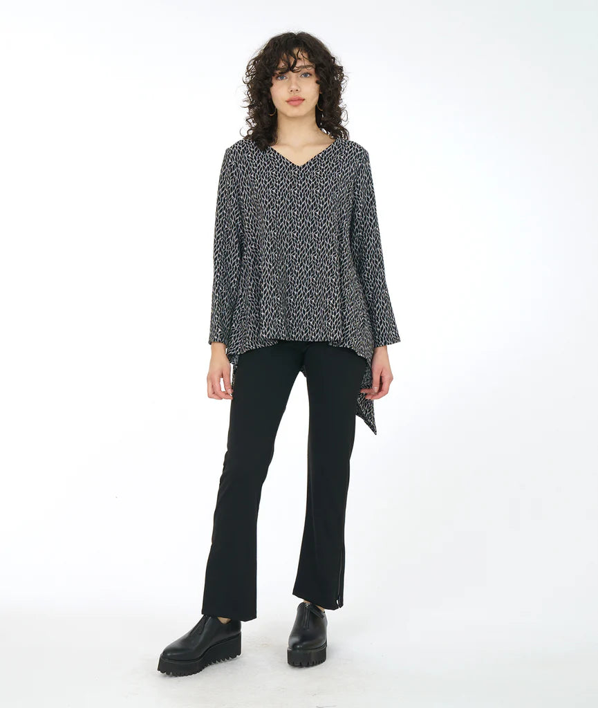 model wearing top in leaf with clean round neckline, straight hem across the front, and longer bias cut points on the back. sleeves go just past the elbow. paired with black pants and shoes. 