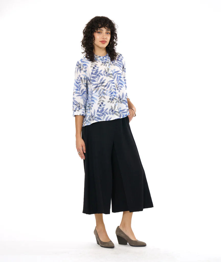 model wearing white button up 3/4 sleeve top with blue and grey leaf print, black pants and grey heels