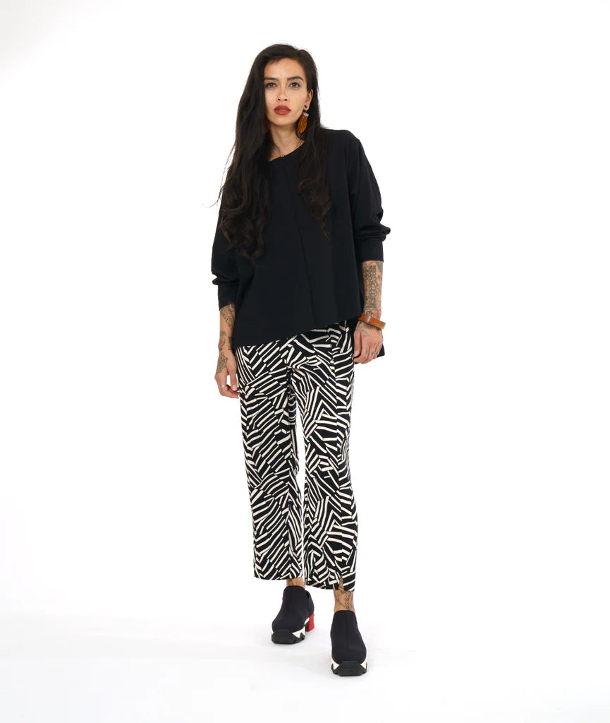 model wearing black top with black and white design pants and sneakers