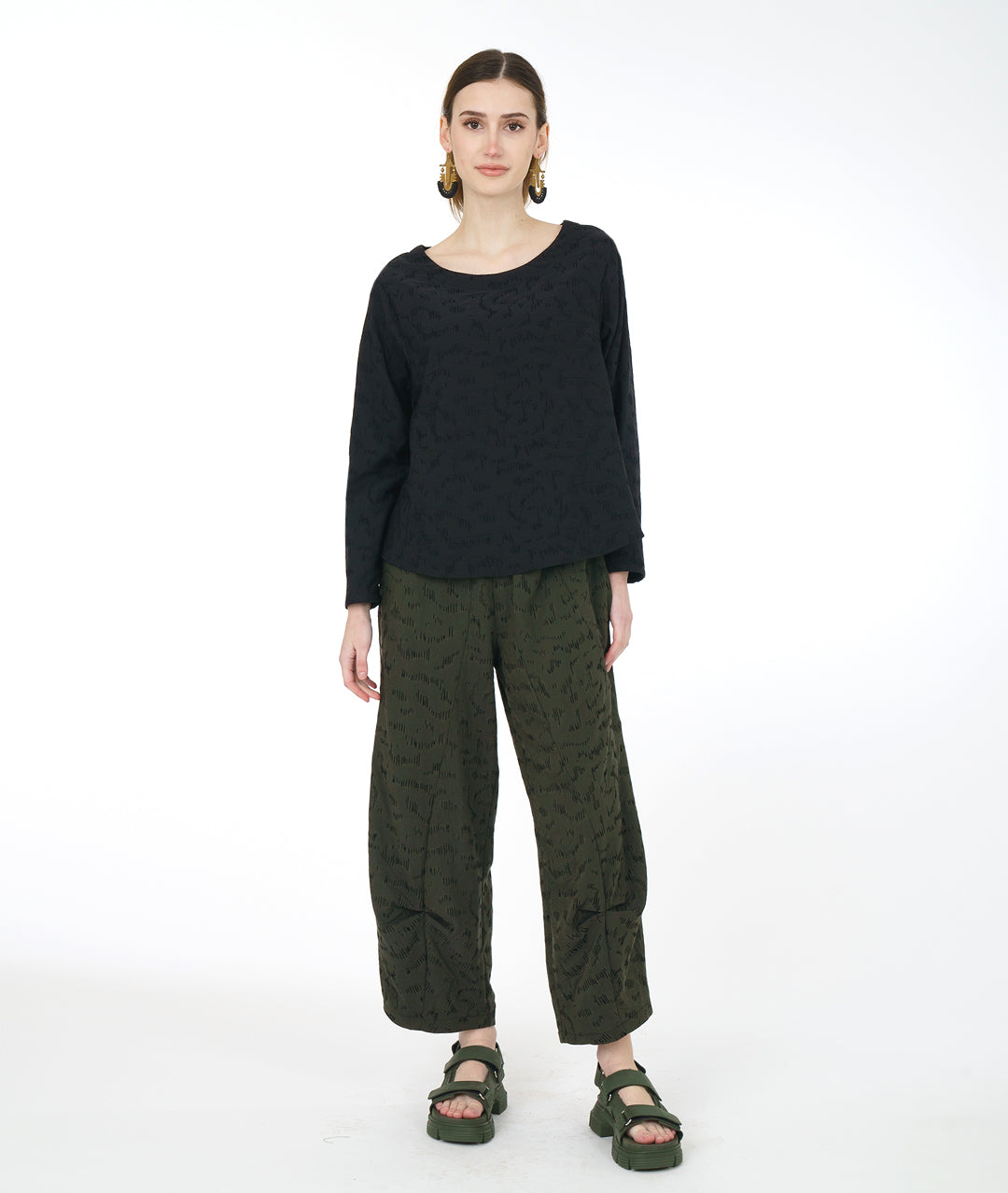 model in a wide leg green pant with a matching black pullover top with a rounded neckline, long sleeves, a boxy body and darts at the bust