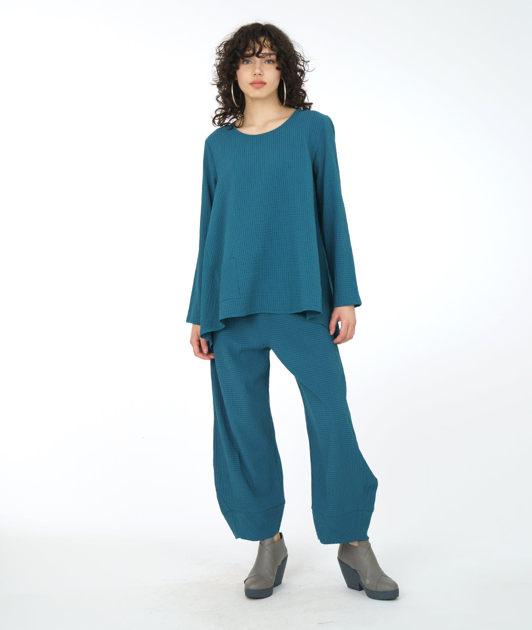 model in a teal flowy top with a matching textured pant with pockets, an elastic waistband, and a tapered cuff at the bottom hem