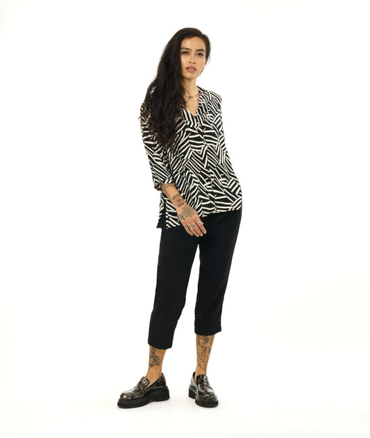 model in a black and white broken stripe print pullover top with 3/4 sleeves and a v-neck. worn with a simple black crop pant