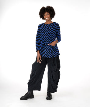 model in a black and blue striped top with a pocket at the waist seam, worn with a wide leg pant