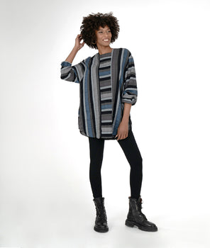 model in a black legging with a multi color striped tunic with long sleeves and a center contrast panel