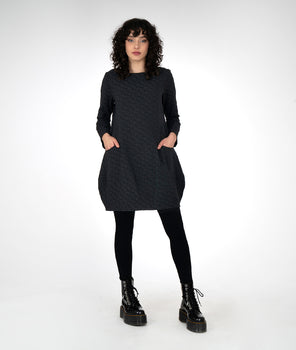 model is wearing a black dress with black leggings and boots