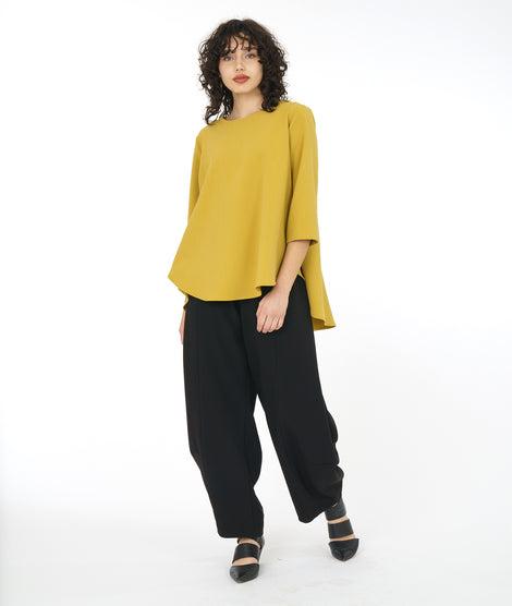 model in a gold yellow pull over top with a high-low hem, 3/4 sleeves and a full bodied back