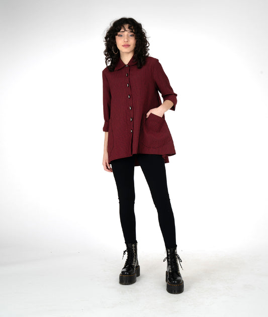 model in a long sleeve button down tunic length blouse, with oversized pockets and a high-low hem