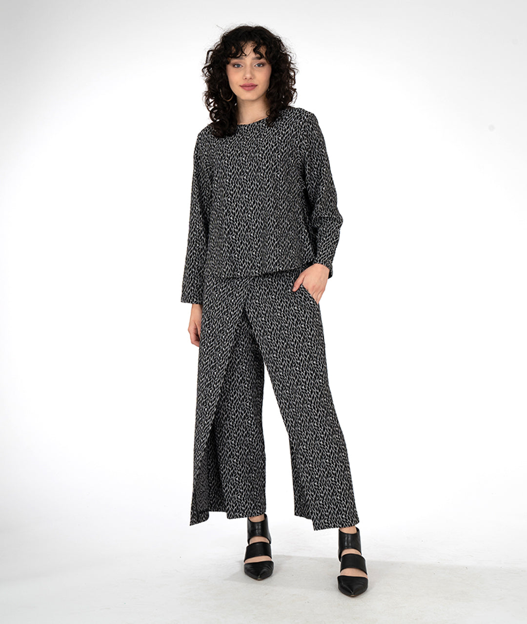 model in a wide leg grey and black leaf print pant with an overlapping front, worn with a matching pullover top with long sleeves and a high round neckline