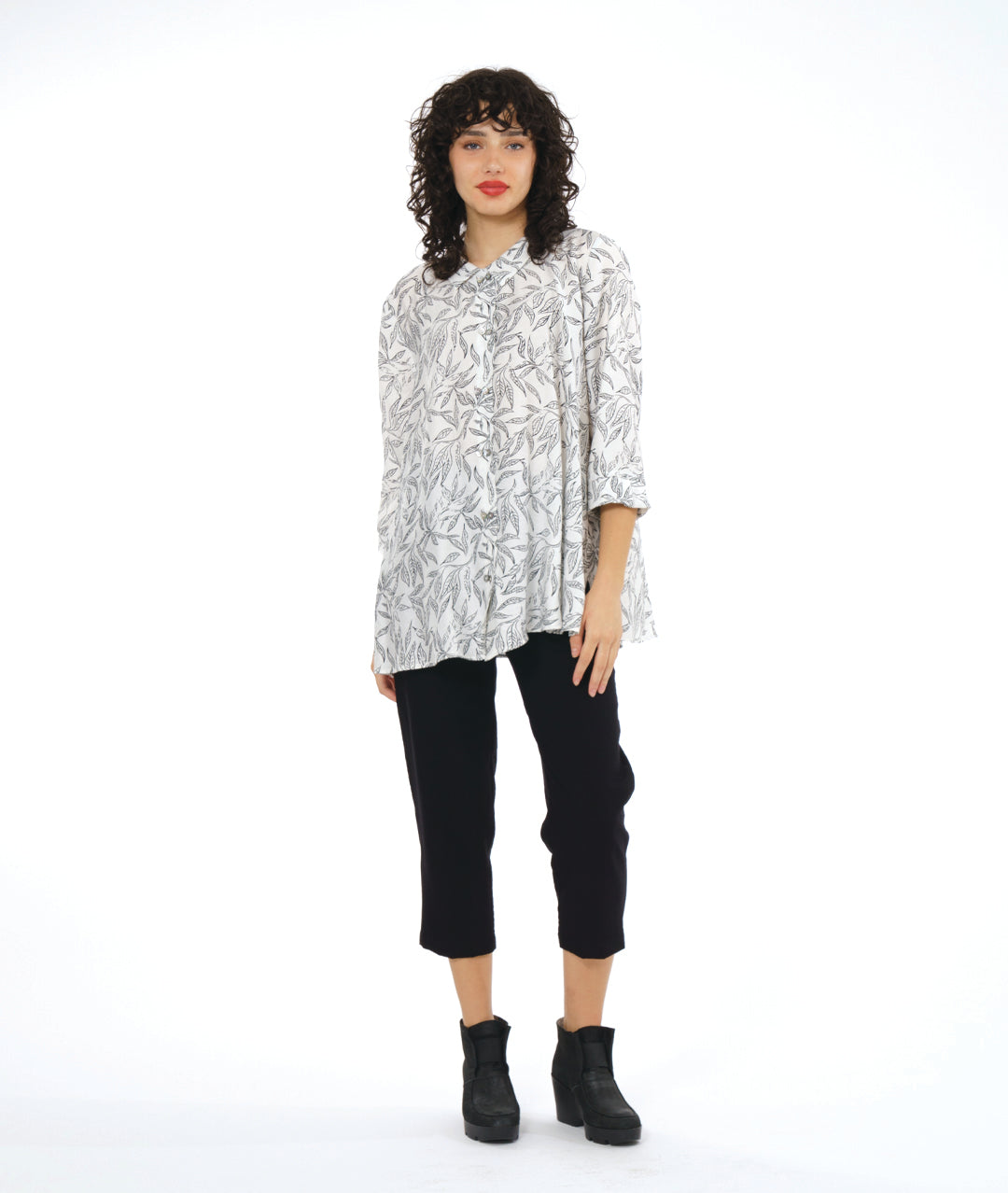 model in a slim black cropped pant, worn with a white button down blouse with a twinbutton detail, 3/4 sleeves, a long body and a floral print