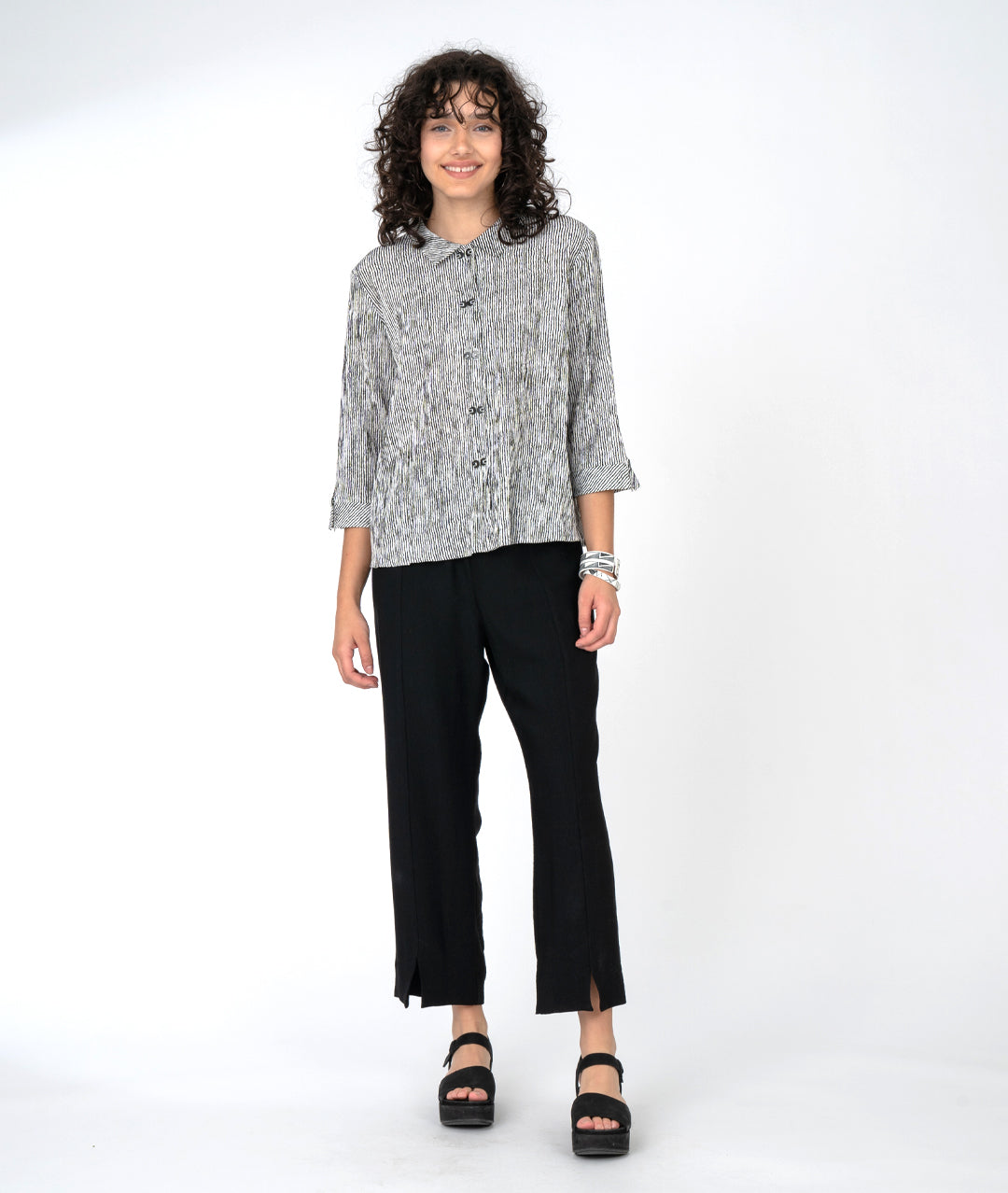 model in a straight leg black pant with a black and white stripe button down blouse with a black twin button down the placket, 3/4 sleeves and a boxy body