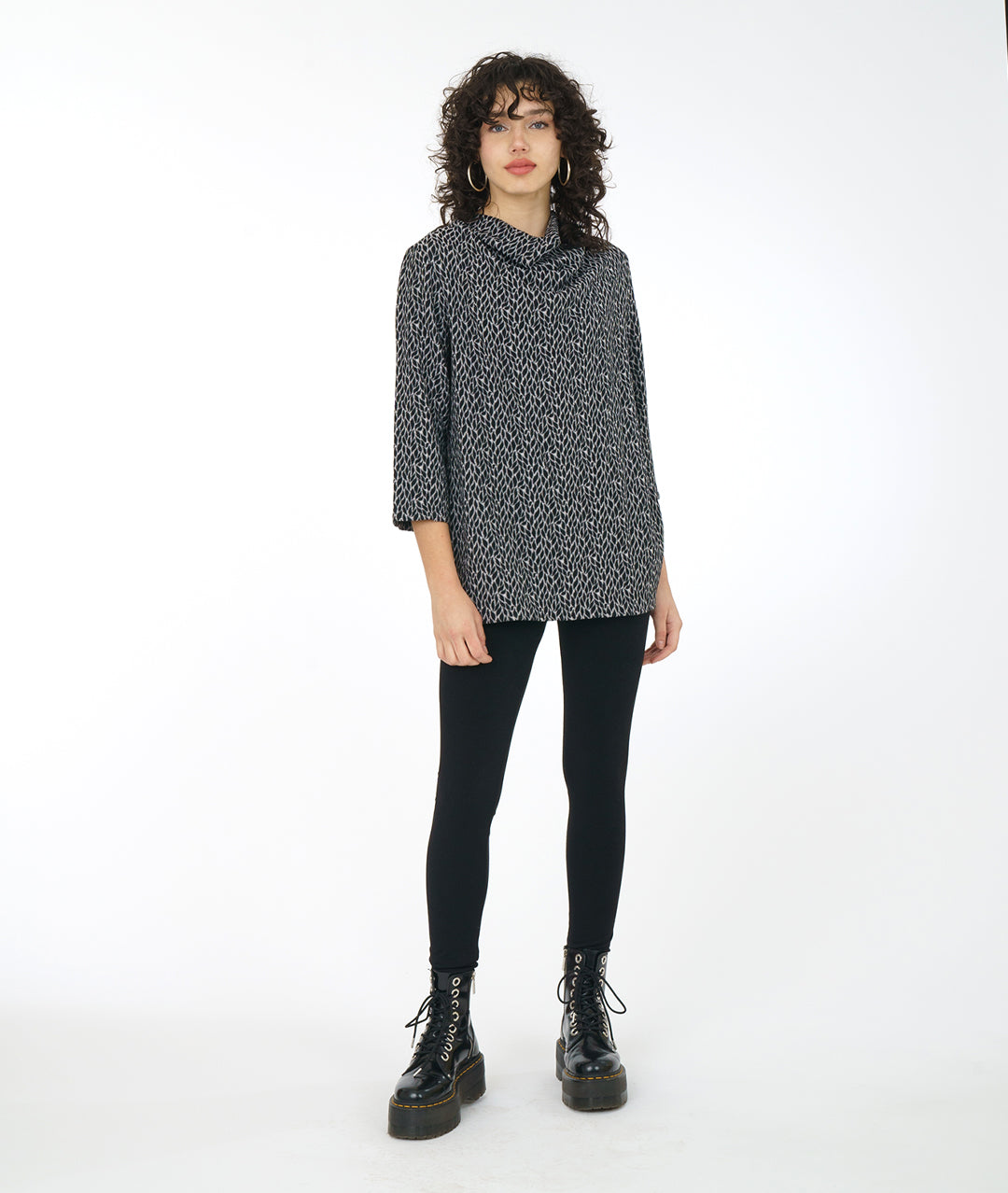 model in a black boot and legging, worn with a grey, black and white leaf print tunic with a 3/4 sleeve and a high cowl neck