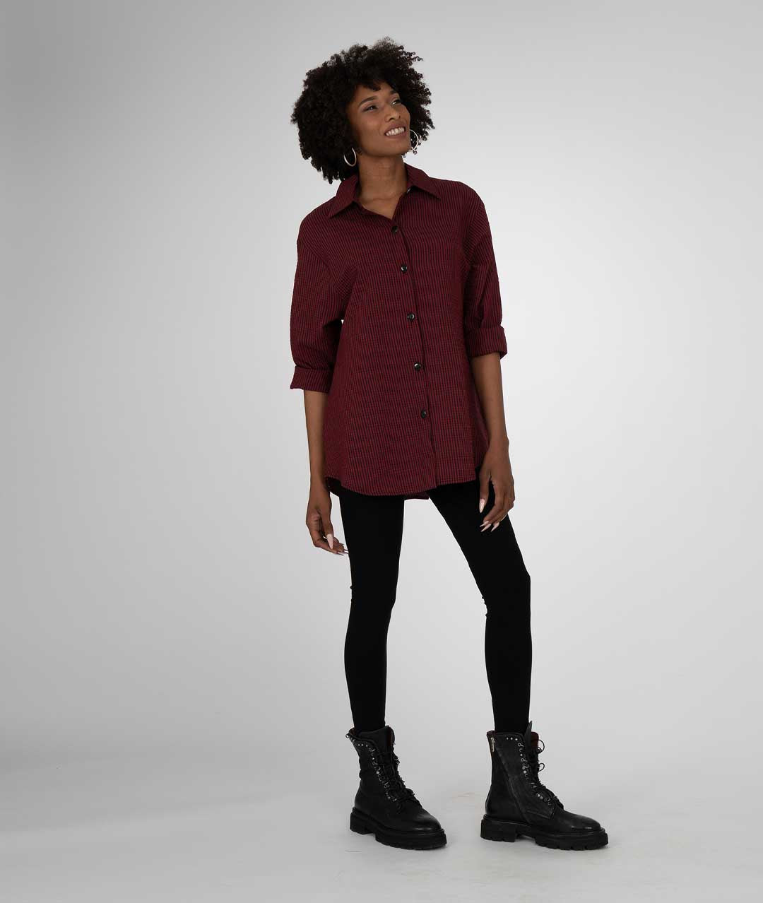 model in a red and black pinstripe long sleeve button down with black leggings