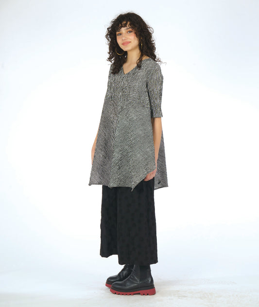model in a wide leg black pant with a textured dot print. worn with a black and white striped blouse