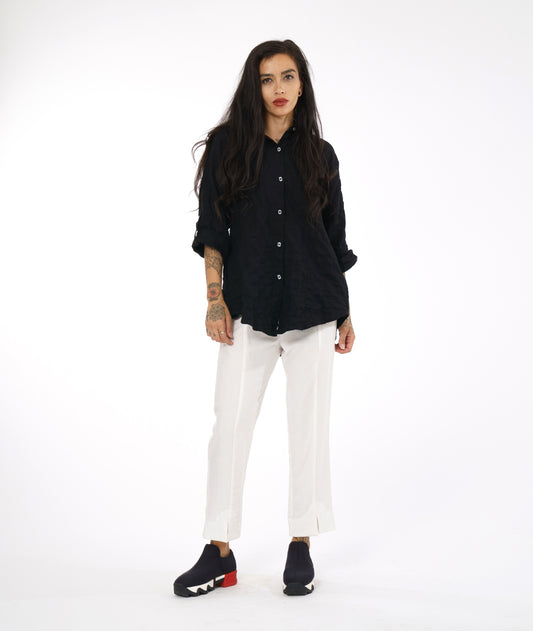 model in a white straight cut pant with a black button down blouse with rolled sleeves