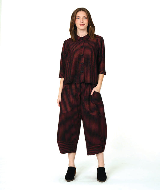 model in a deep red and black striped blouse with a matching wide leg pant with tapered ankles and oversized contrasting pockets