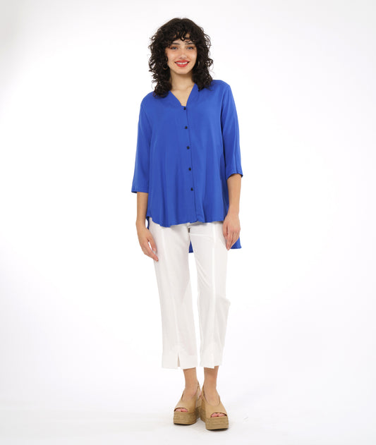 model in a white slim cut pant with a periwinkle button down blouse with 3/4 sleeves and a rounded hem, lower in the back