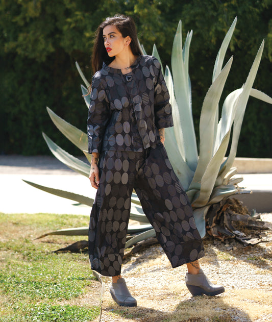 model in a grey oval print wide leg pant with a tapered ankle, worn with a matching jacket with 3/4 sleeves and a single button closure at the neckline