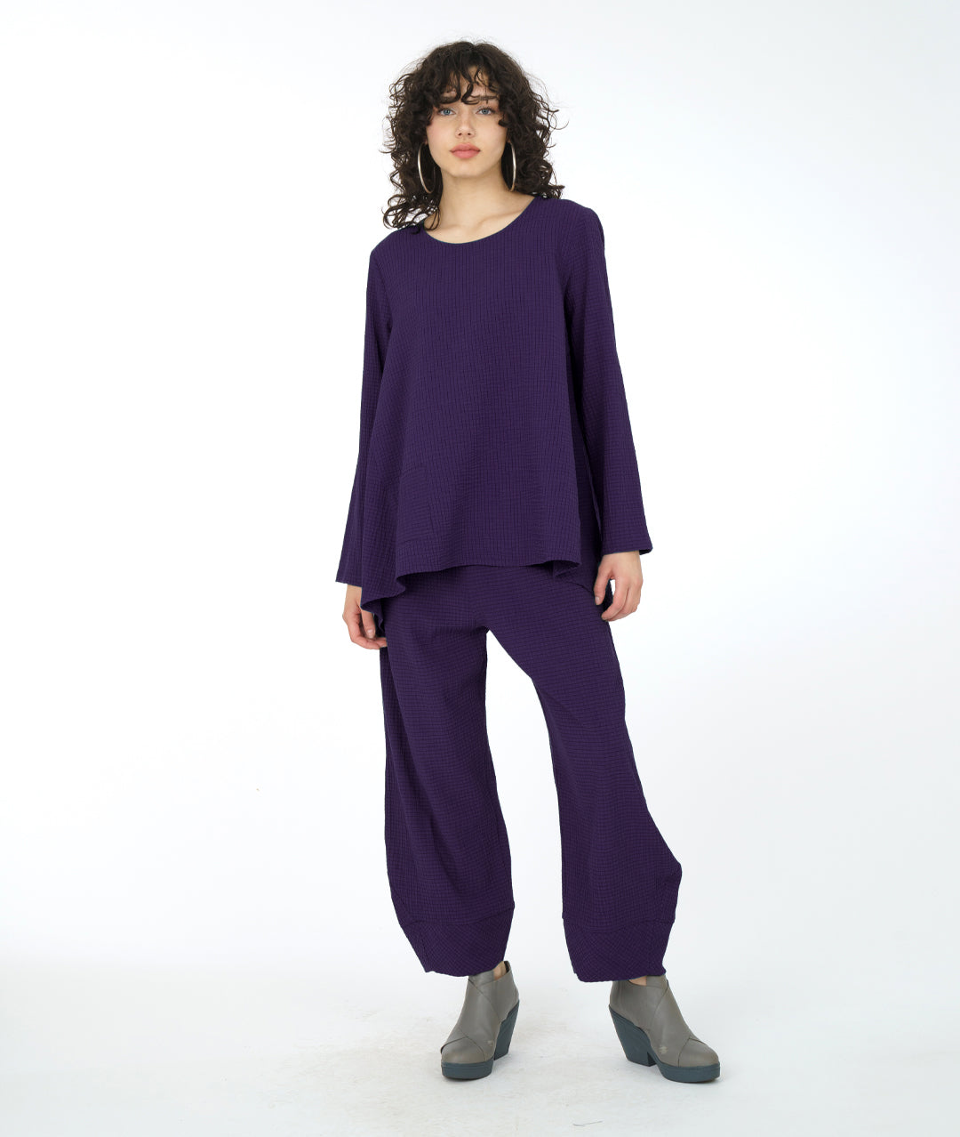 model in a dark purple full bodied pull over with a single square pocket at the hip, in a matching wide leg pant 