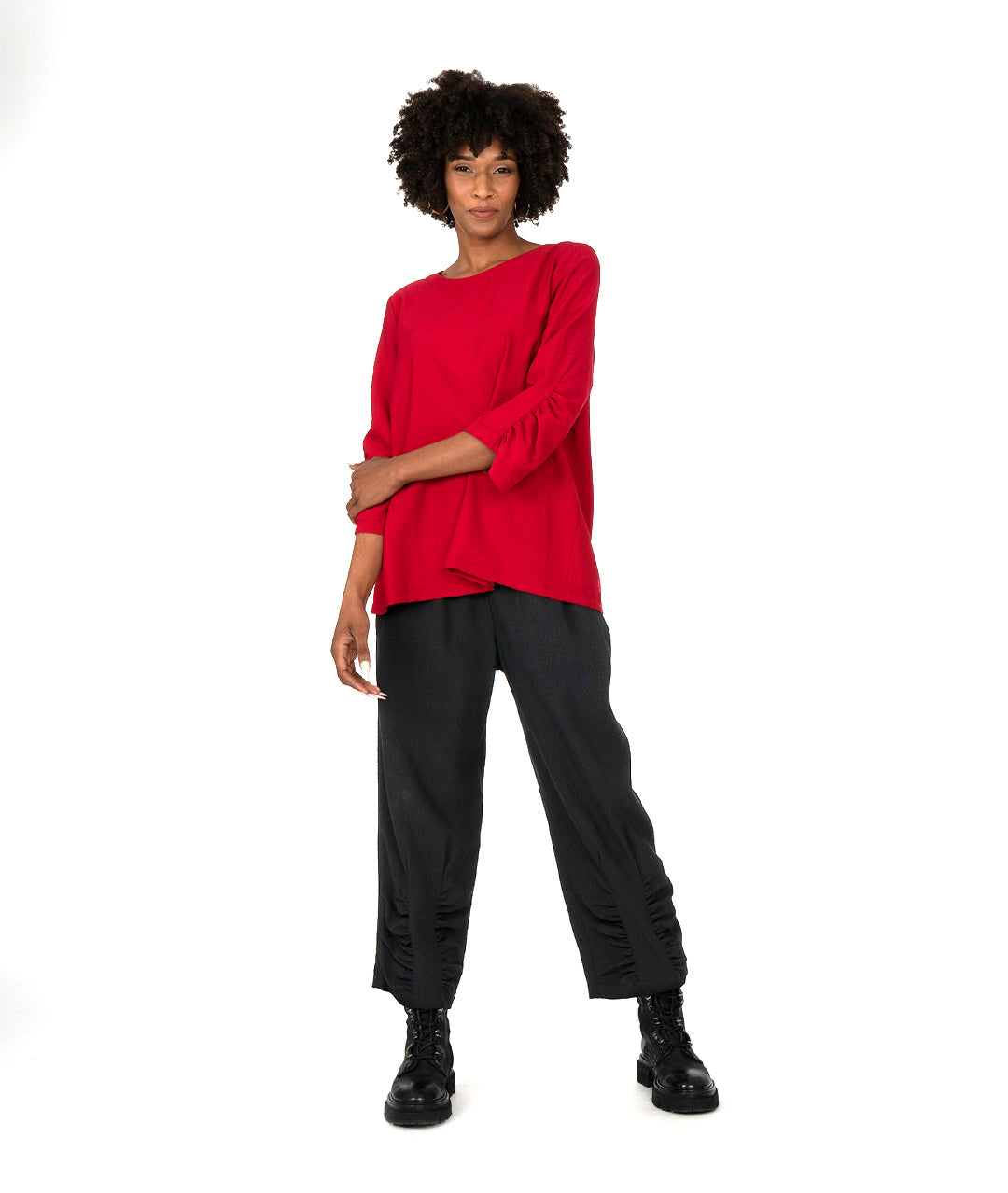 model in a red top with a rouching detail on the arms and a matching black pant with the same detail