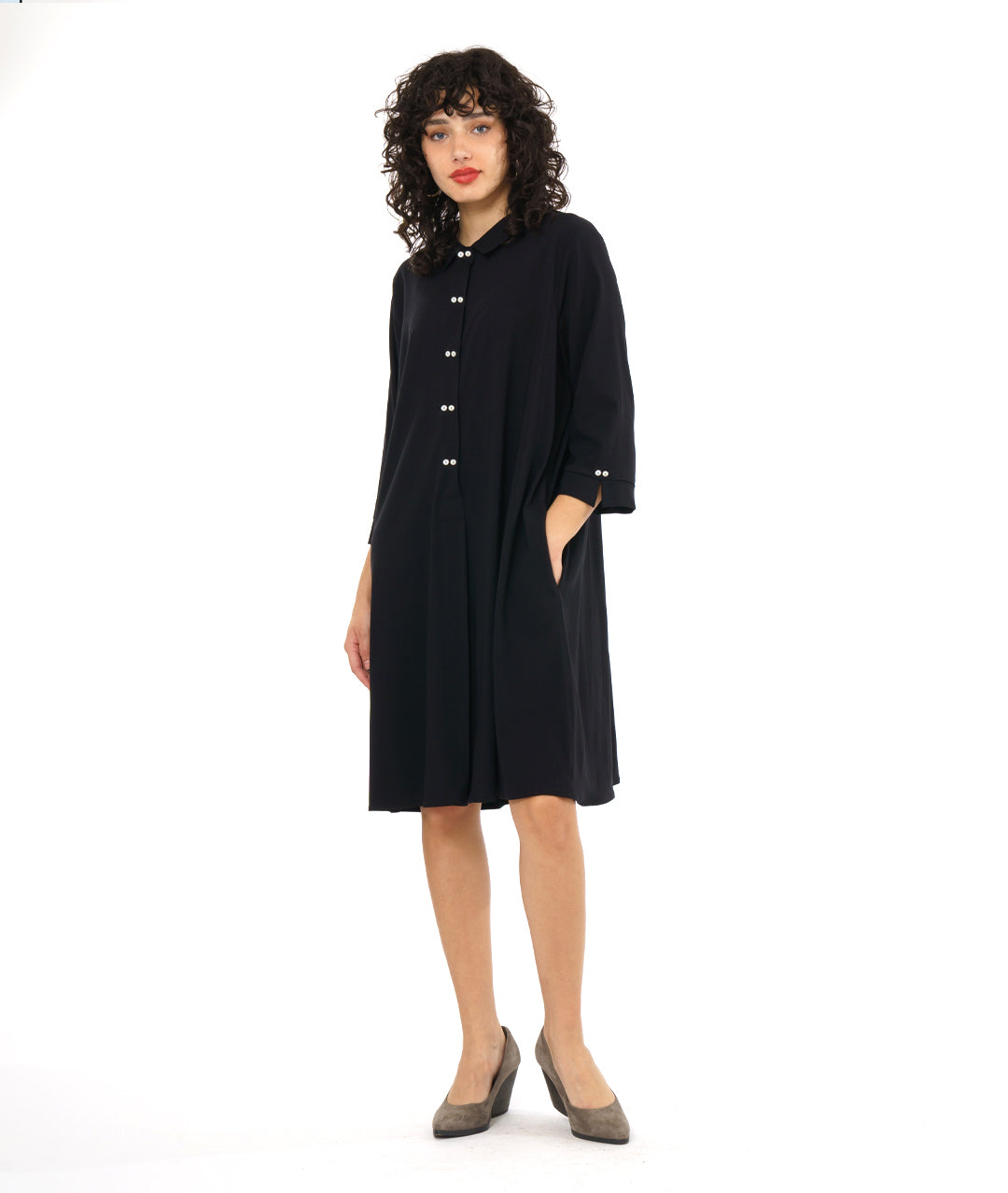 model in a black, knee length button down shirt dress with 3/4 sleeves and a twin button detail