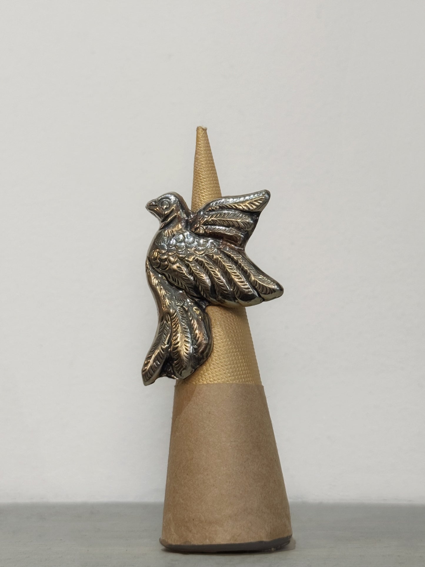 silver bird ring on a cone-shaped base against a plain background