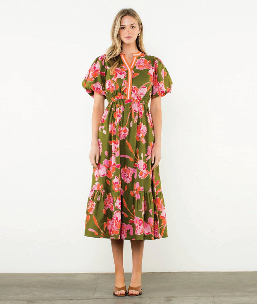 Woman wearing a olive green floral puff sleeve dress with a white background