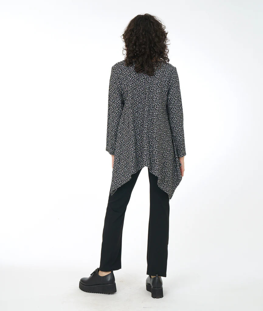 model wearing top in leaf with clean round neckline, straight hem across the front, and longer bias cut points on the back. sleeves go just past the elbow. paired with black pants and shoes. 