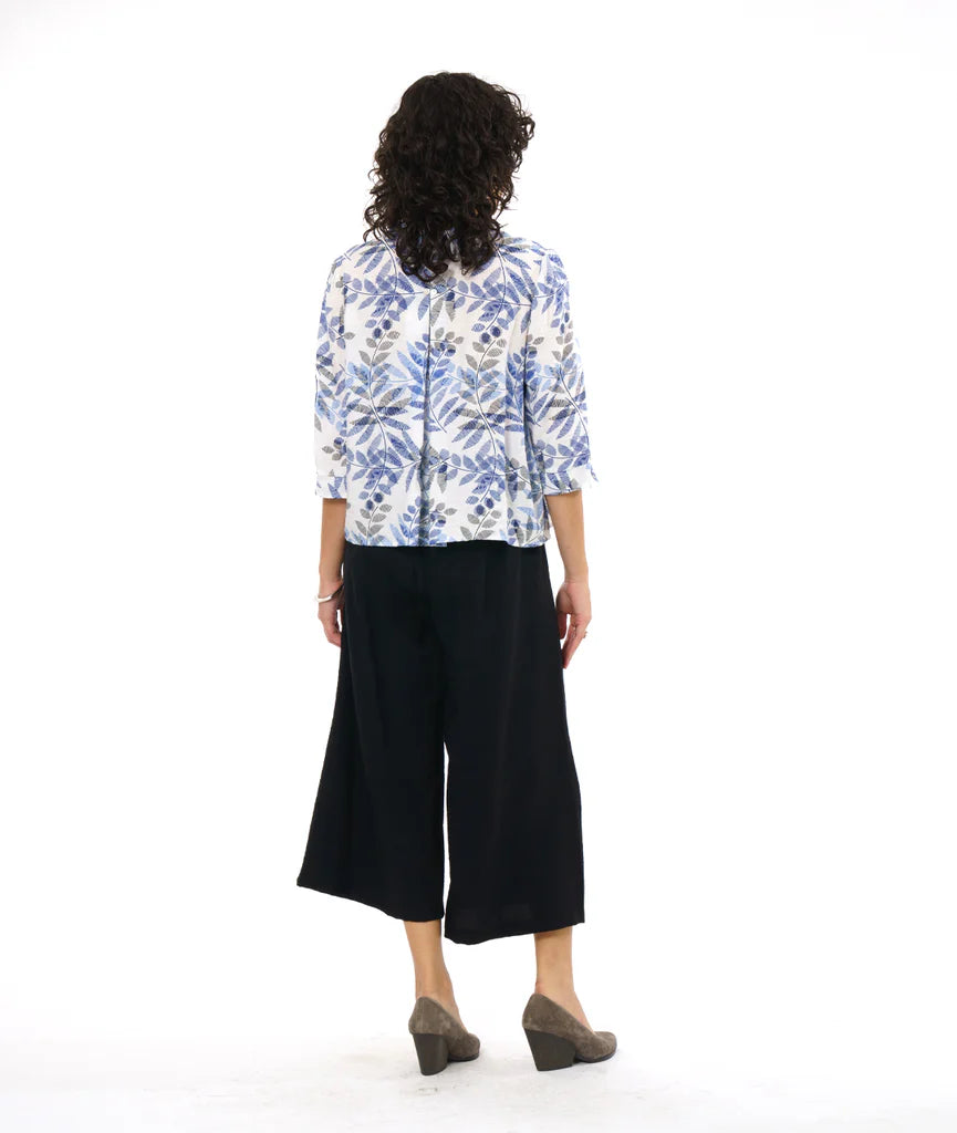 model showing back of white button up 3/4 sleeve top with blue and grey leaf print, paired with black pants and grey heels