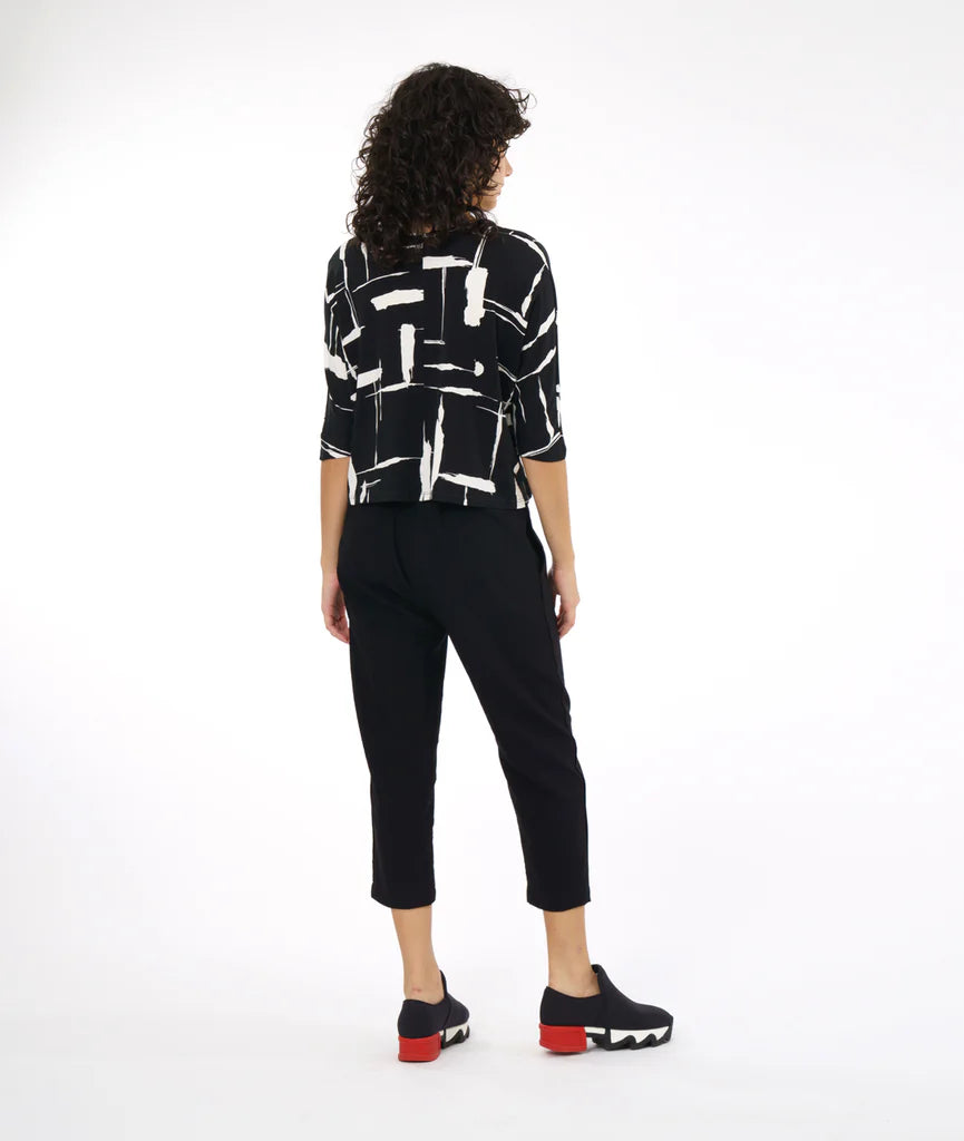 model showing back of black and white print top with boxy cut and dolman sleeves paired with black pants and sneakers