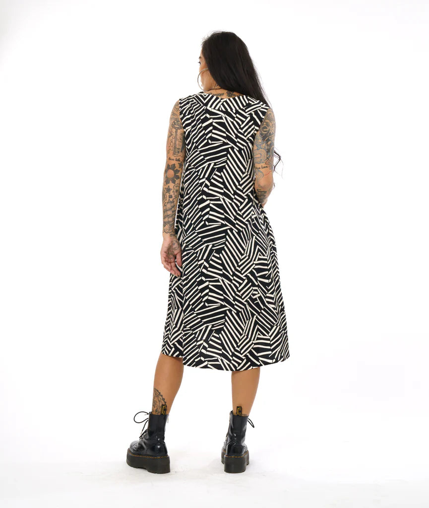 model showing back of v neck mid length dress with black and white design, paired with black boots