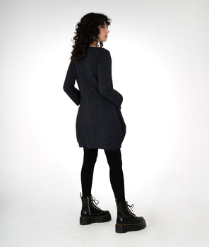 model is wearing a black dress with black leggings and boots