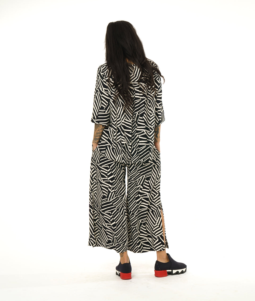 model in a black and white broken stripe print pant, worn with a collar less matching fabric button down blouse with 3/4 sleeves