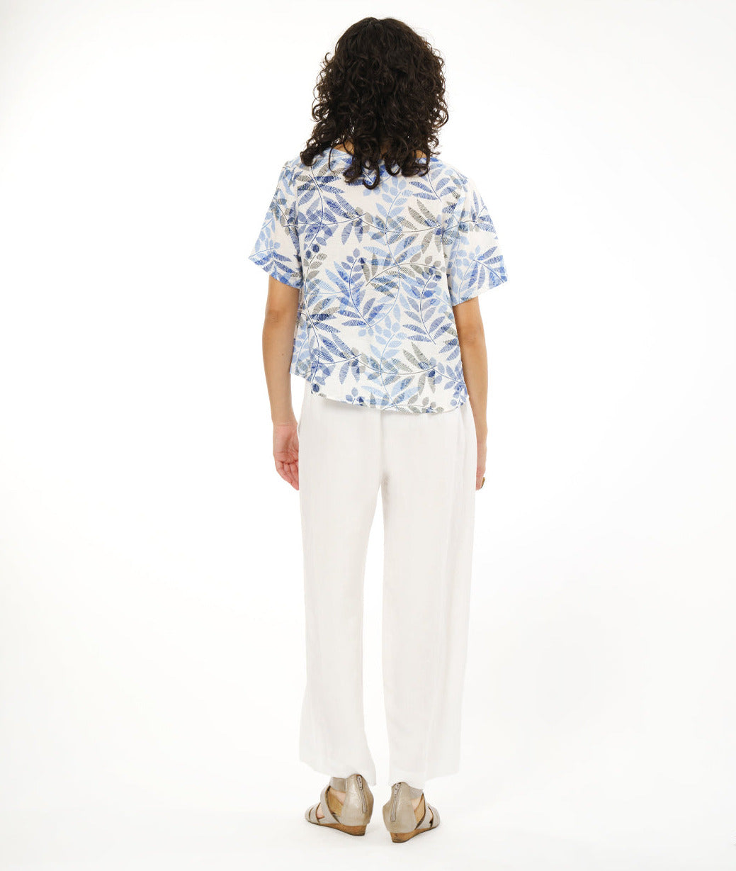 model in a wide white pant with a boxy pullover tee in white, with a blue and black leaf print