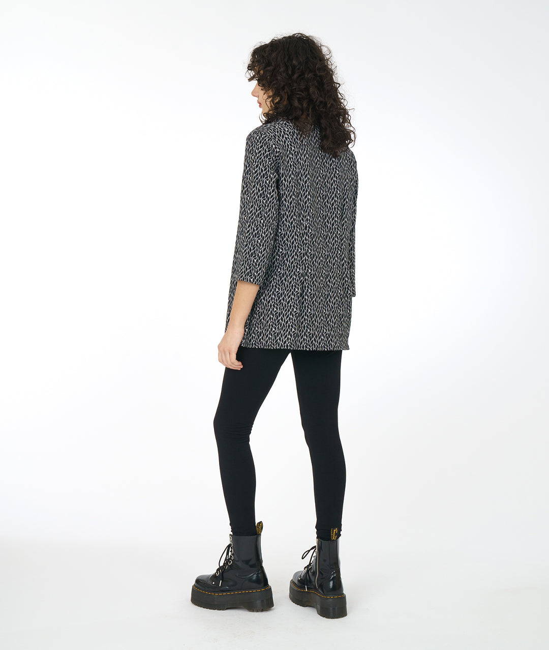 model in a black boot and legging, worn with a grey, black and white leaf print tunic with a 3/4 sleeve and a high cowl neck