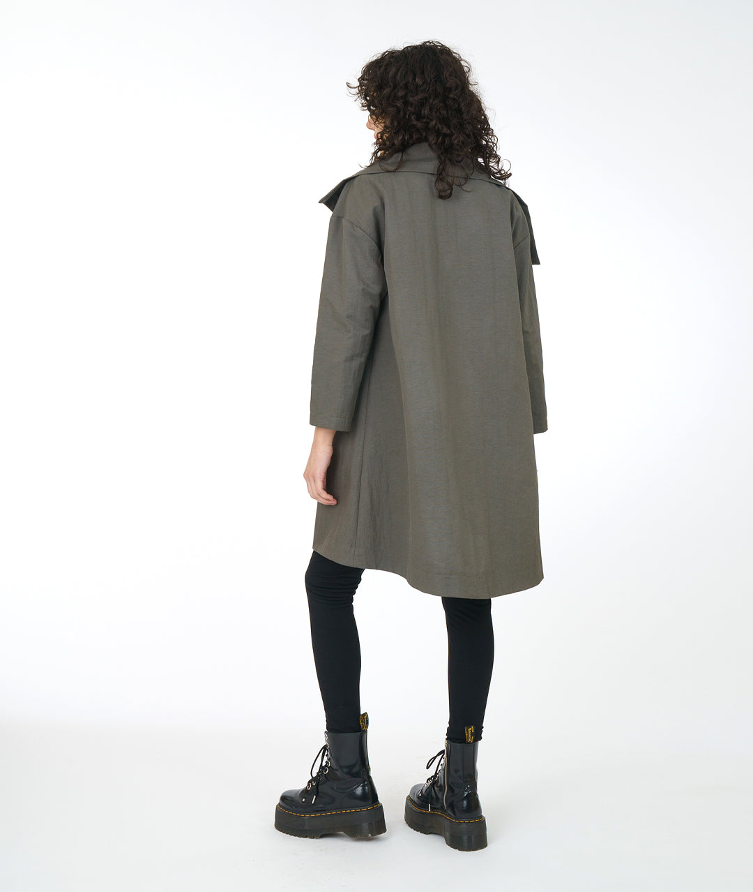model in a black legging and top, worn with a grey jacket with an oversized collar and asymmetrical pocket detail