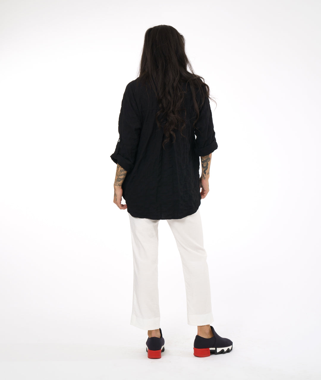 model in a white straight cut pant with a black button down blouse with rolled sleeves
