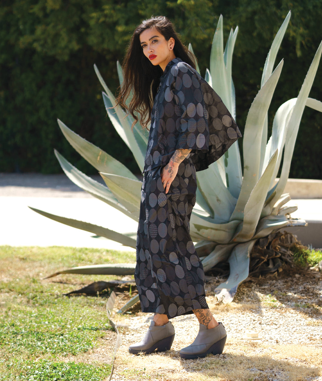 model in a grey oval print wide leg pant with a tapered ankle, worn with a matching jacket with 3/4 sleeves and a single button closure at the neckline