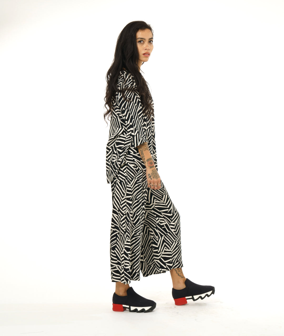 model in a black and white broken stripe print pant, worn with a collar less matching fabric button down blouse with 3/4 sleeves