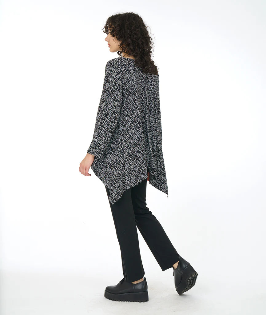 model wearing top in leaf with clean round neckline, straight hem across the front, and longer bias cut points on the back. sleeves go just past the elbow. paired with black pants and shoes. 