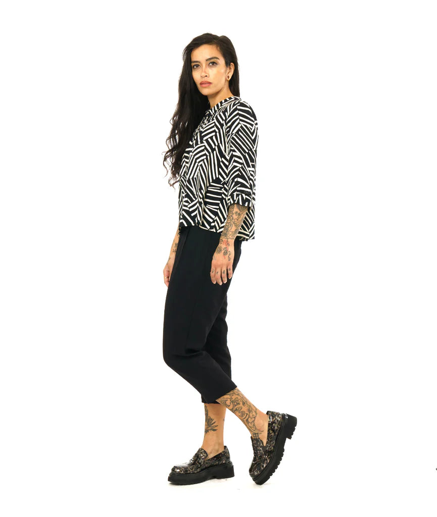 model wearing black and white design button up 3/4 sleeve top with black pants and loafers