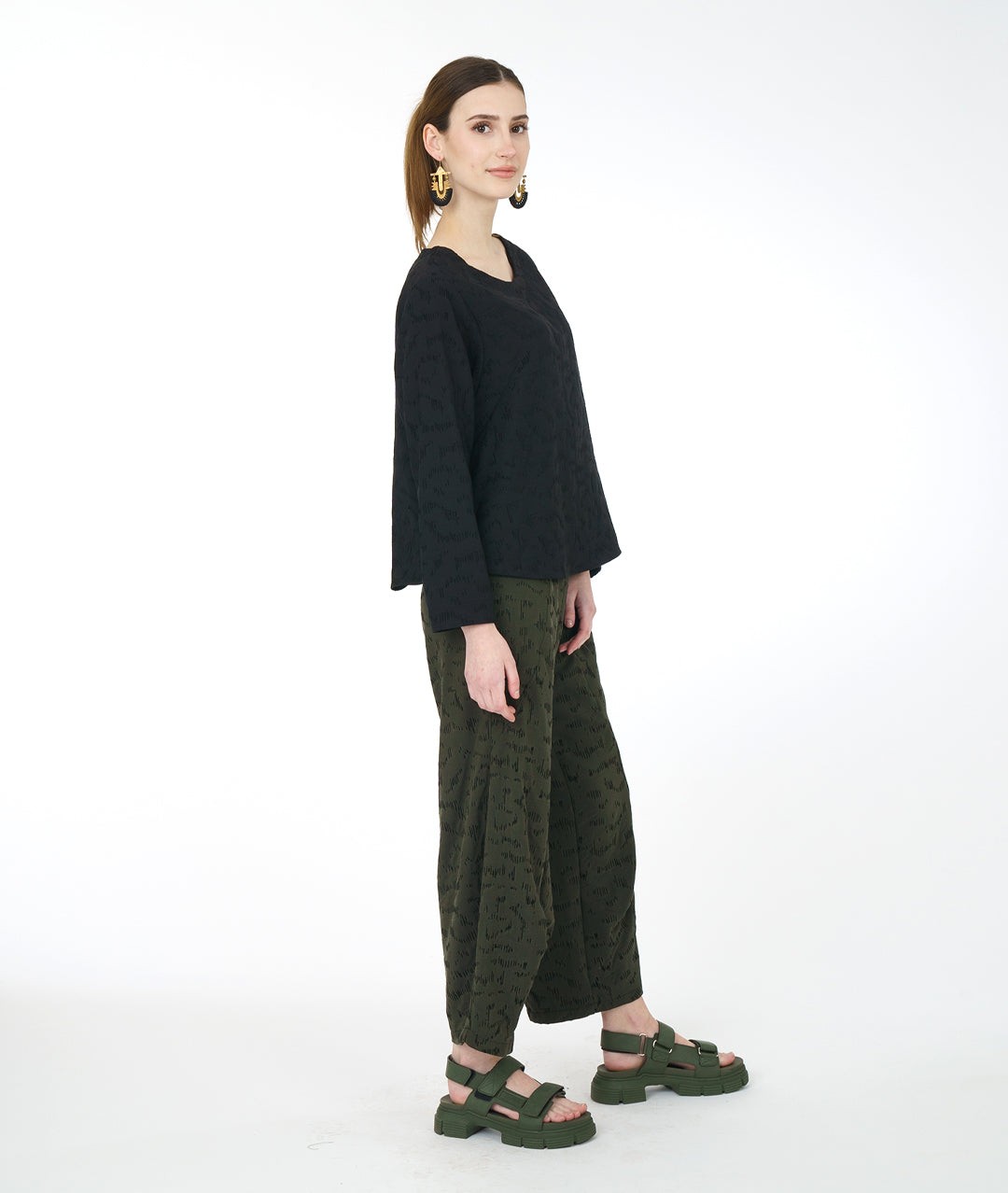 model in a wide leg green pant with a matching black pullover top with a rounded neckline, long sleeves, a boxy body and darts at the bust