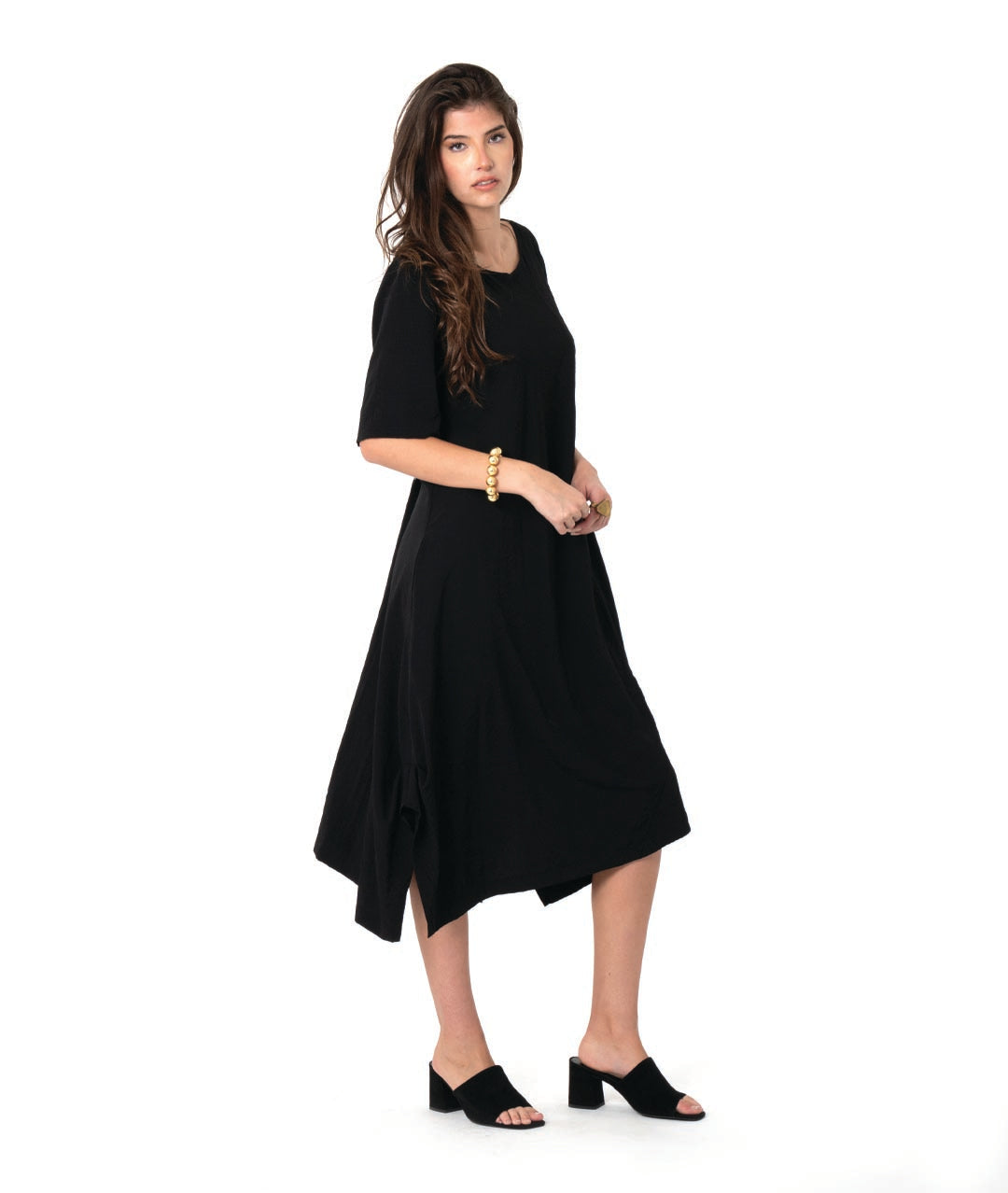 model in a pullover black dress with a slight grid texture. dress has a rounded neck, elbow length sleeves, and a flowy skirt with tucks and splits