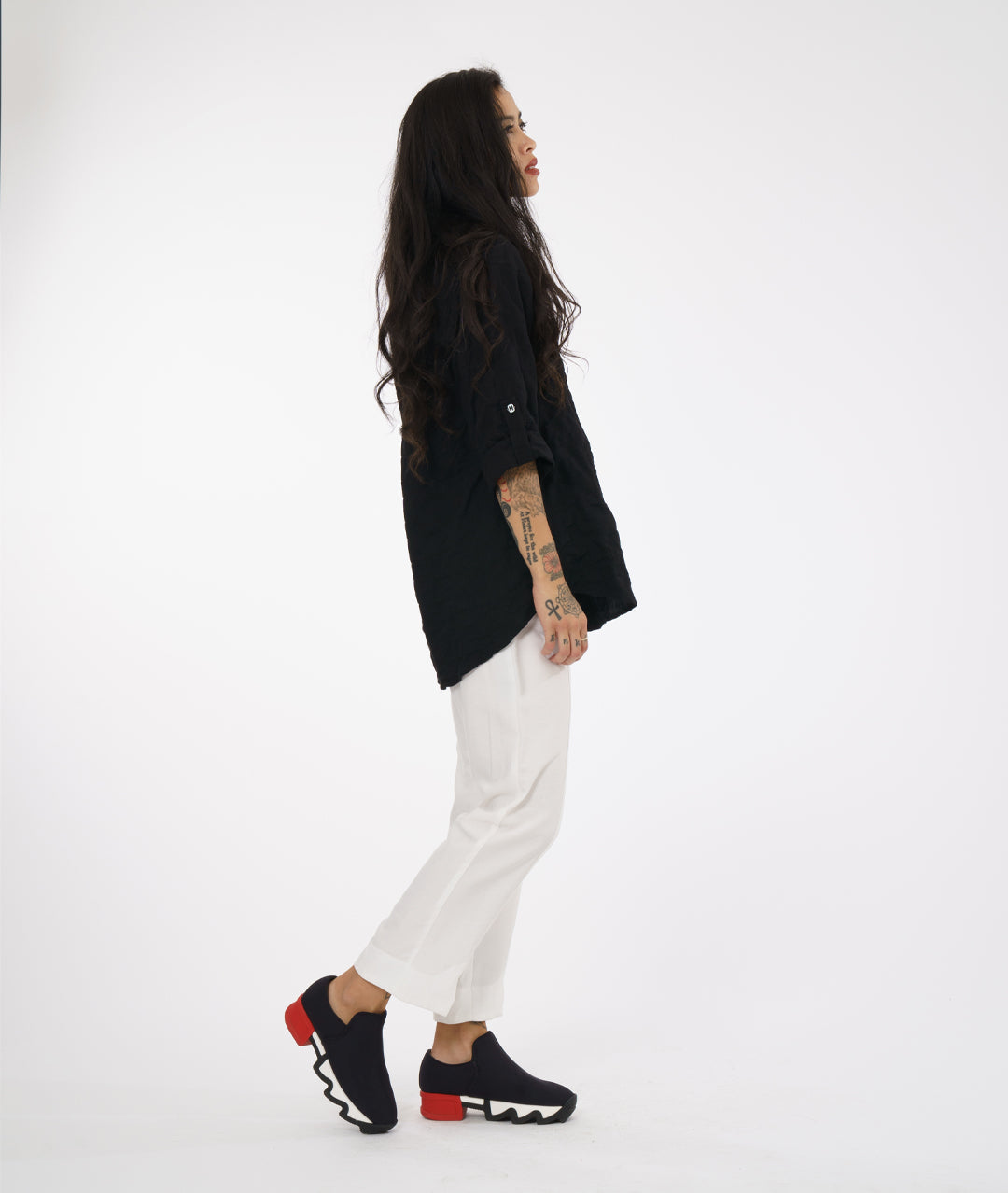 model in a white straight cut pant with a black button down blouse with rolled sleeves