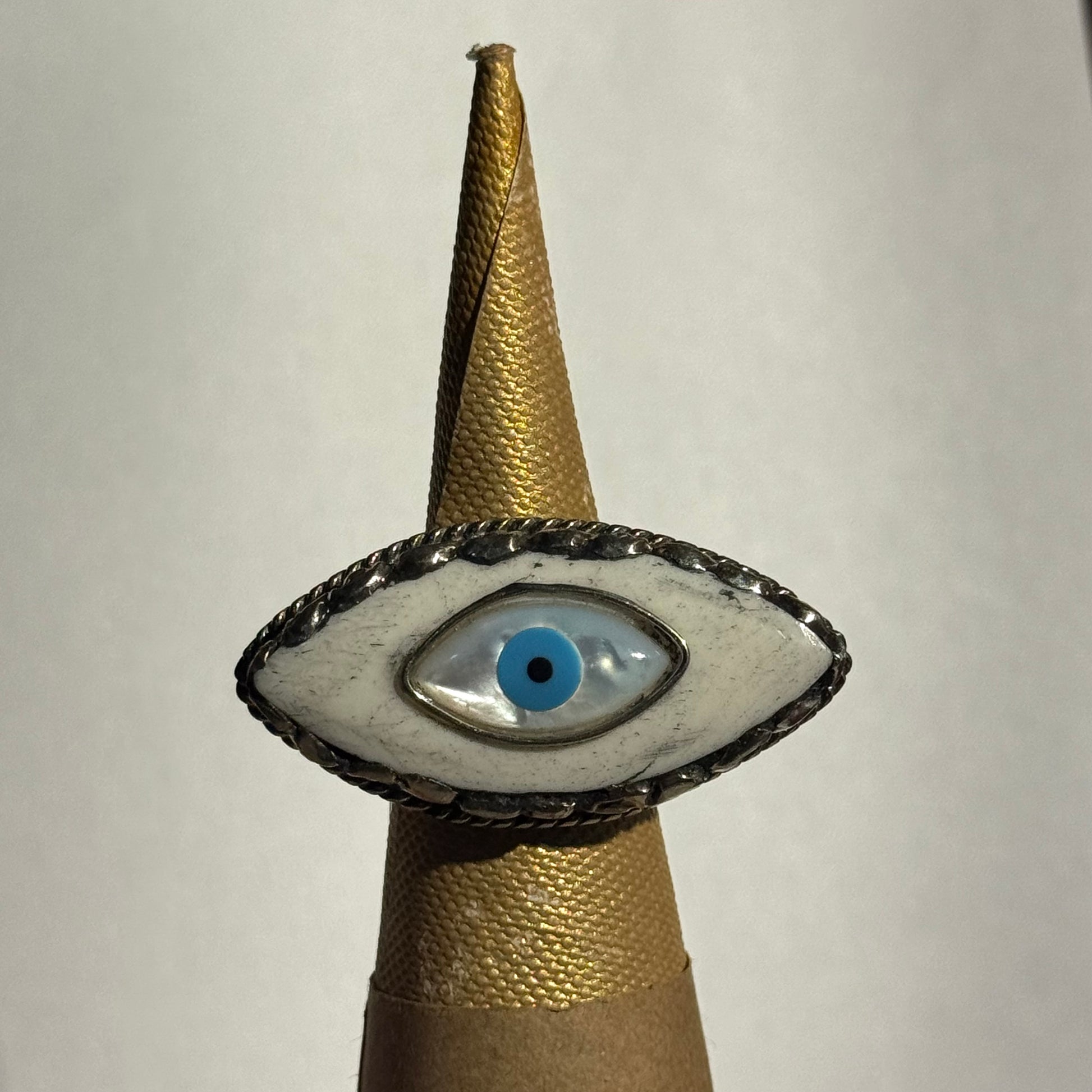 eye design ring on a ring holder cone against a white background