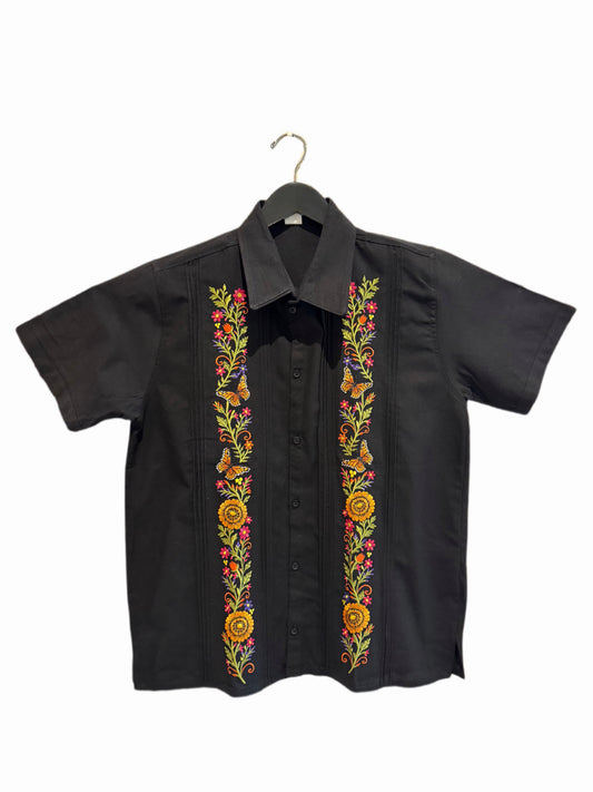 A black short-sleeve button-up shirt hanging on a black hanger, featuring vibrant multicolor floral embroidery running down both front panels.