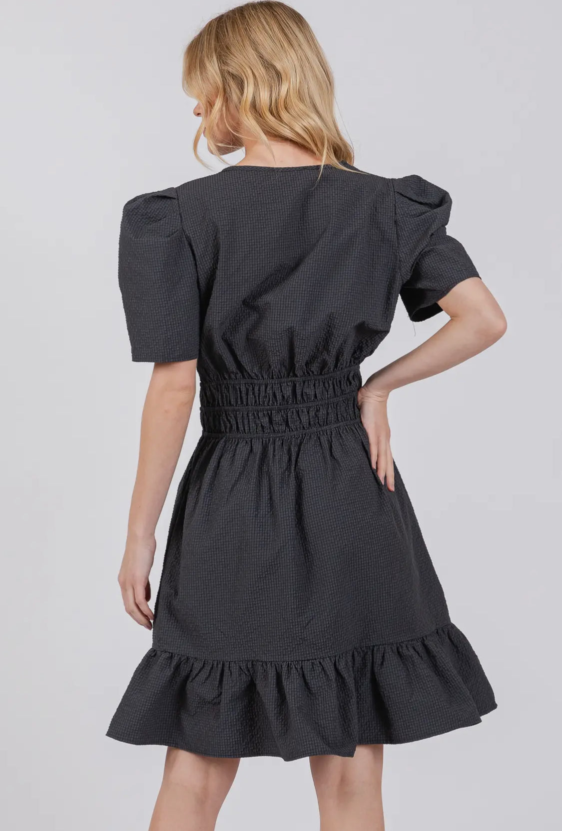 model showing back of black puff sleeved ruffle dress